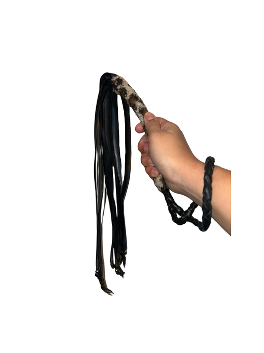 Hand holding the bold Animal Print Vegan Flogger, made from recycled bike tires, combining sustainability with fierce design.