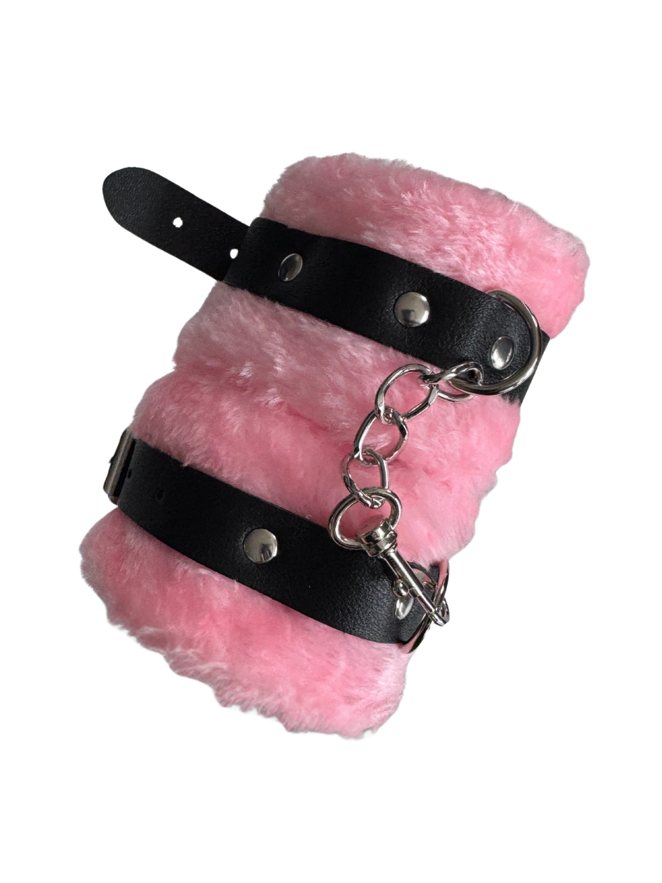 Rolled up fluffy pink handcuffs showing plush material and secure D-rings — non-intimidating, inclusive sex toy for couples.