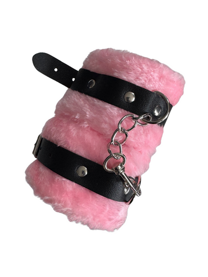 Rolled up fluffy pink handcuffs showing plush material and secure D-rings — non-intimidating, inclusive sex toy for couples.